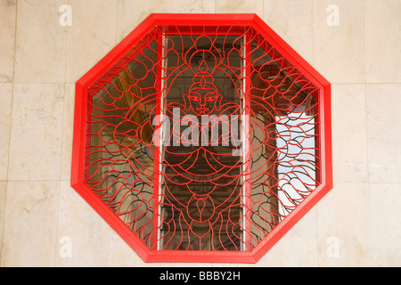 Octagonal window with lattice work showing Buddha Stock Photo