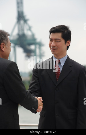 Businessmen standing face to face, shaking hands Stock Photo