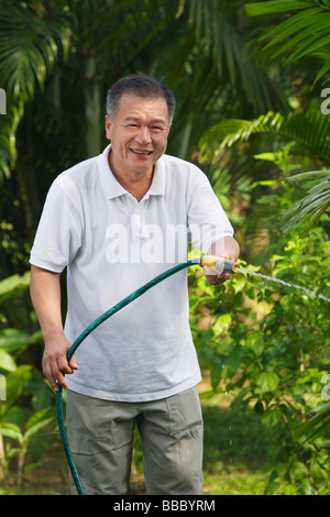 Man with hose, watering garden Stock Photo