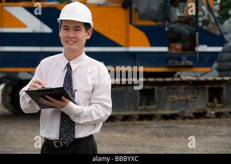 Man with hard helmet and clipboard looking at camera Stock Photo