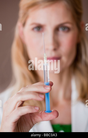 female medic looking at syringe Stock Photo