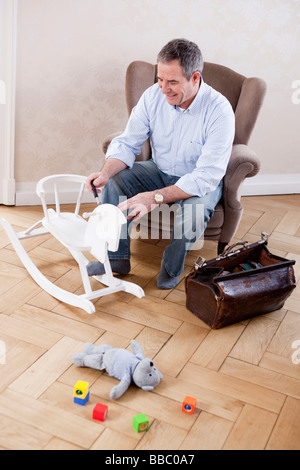 man sitting in chair repairing toys Stock Photo