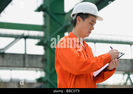 Construction worker making notes on clipboard Stock Photo