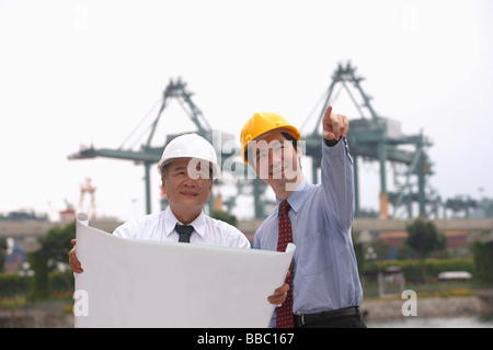Men with helmets and blueprints Stock Photo