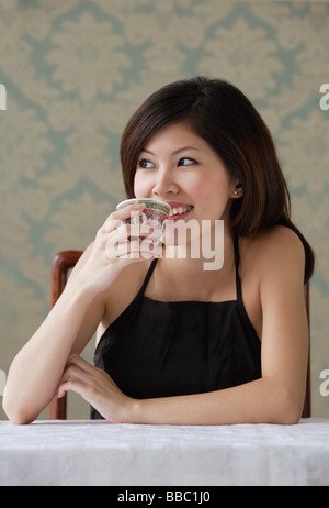 Young woman drinking tea looking sideway Stock Photo