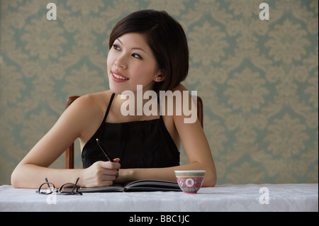 Young woman looking sideways while writing Stock Photo