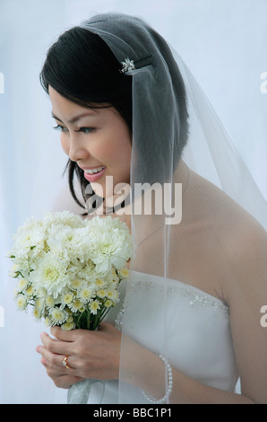 A bride smiles as she holds a bouquet of flowers Stock Photo