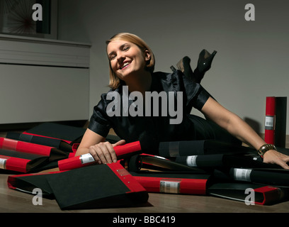 Woman laying in pile of binders Stock Photo