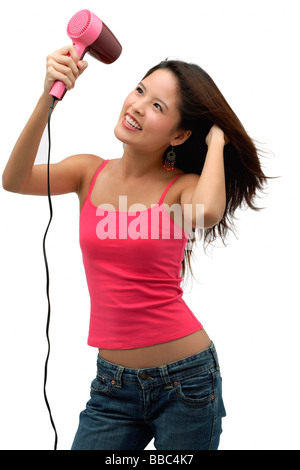 Young woman blow drying hair and smiling Stock Photo