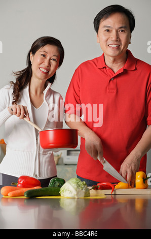 Mature couple in kitchen, preparing a meal together, smiling at camera Stock Photo