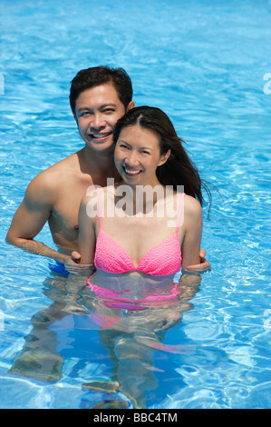 Couple in swimming pool, smiling at camera Stock Photo