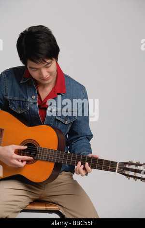 Man in denim jacket, playing guitar Stock Photo
