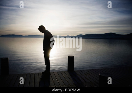 Man standing on pier at sunset Stock Photo