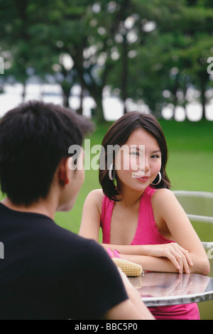 Woman smiling at camera, arms crossed, man in foreground Stock Photo