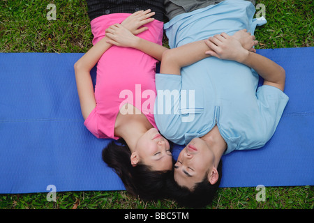 Couple in park, lying on mat, eyes closed Stock Photo