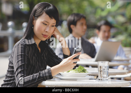 Businesswoman using mobile phone at outdoor cafe, text messaging Stock Photo