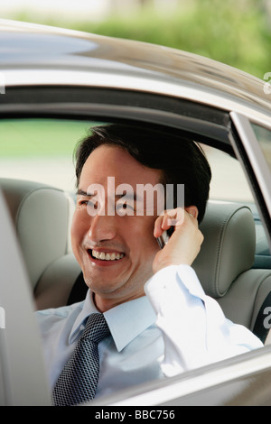 Businessman sitting in car, using mobile phone Stock Photo