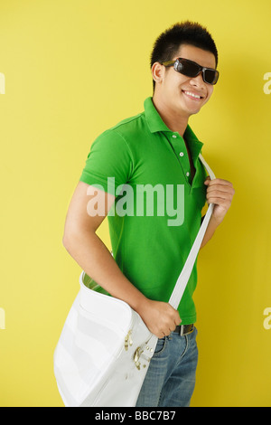 Man in green polo shirt, standing against yellow background, sunglasses on Stock Photo