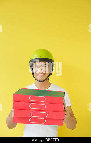 Pizza delivery person carrying a stack of pizza boxes Stock Photo