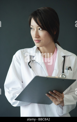 Female doctor, holding clipboard, looking away Stock Photo