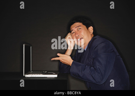 Businessman pointing at laptop next to him Stock Photo