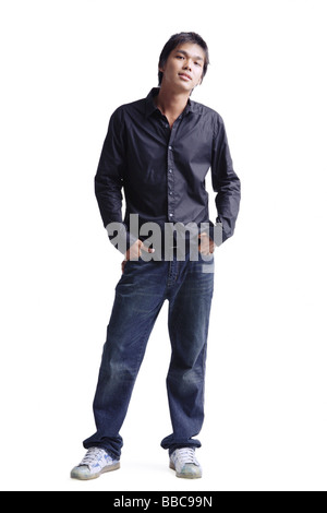 Young man standing, hands in pocket, looking at camera Stock Photo