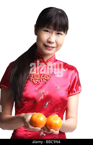 Woman in Cheongsam, holding two oranges Stock Photo