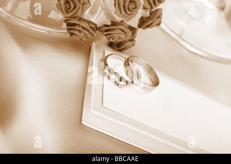gold wedding and diamond engagement ring on blank a wedding card sepia toned Stock Photo
