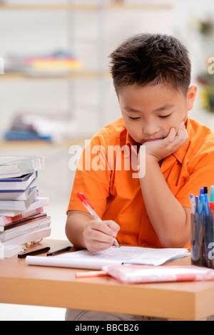 Boy sitting at desk, doing homework Stock Photo