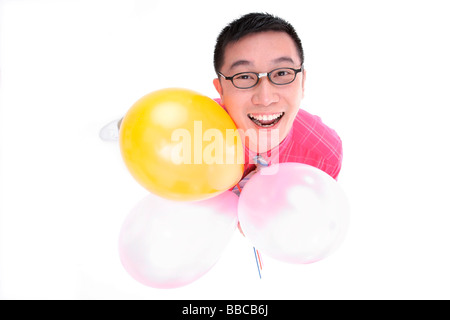 Man holding balloons, looking up at camera Stock Photo