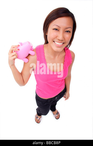 Smiling young woman with piggy bank pointing her finger Stock Photo - Alamy