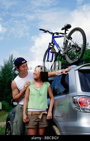 Couple standing next to SUV, looking at each other Stock Photo
