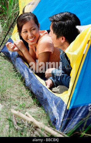 Couple lying in tent, smiling at each other Stock Photo