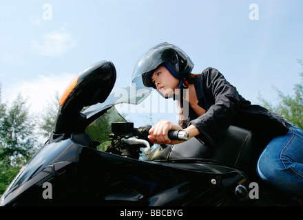 Young woman riding motorbike, low angle view Stock Photo