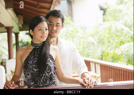 Couple standing together next to railing, man behind woman Stock Photo