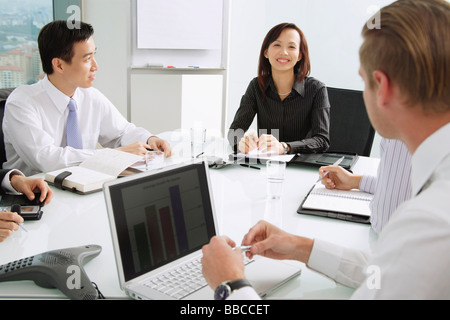 Businesswoman at head of table, smiling, male executives sitting around her Stock Photo