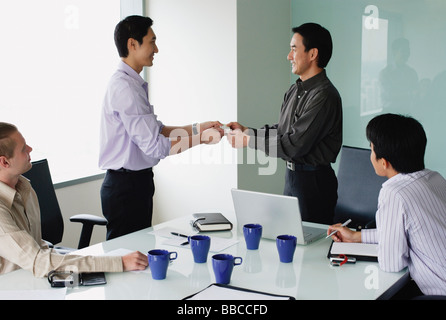 Executives in meeting room, exchanging business cards Stock Photo