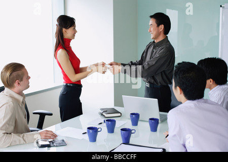 Executives exchanging business cards in meeting room Stock Photo