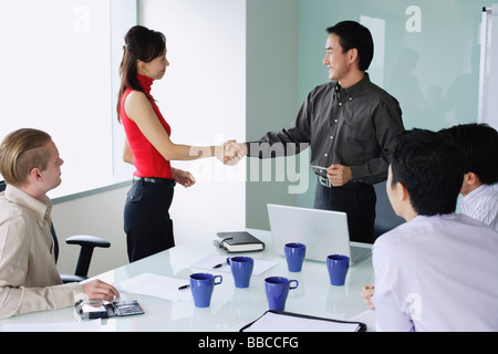 Executives exchanging shaking hands in meeting room Stock Photo