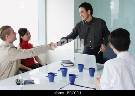 Executives in meeting room, two men shaking hands Stock Photo