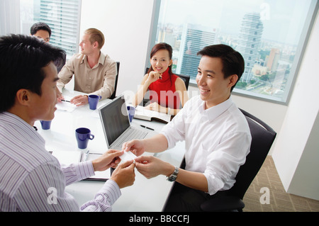 Executives around conference table, two businessmen exchanging business cards Stock Photo