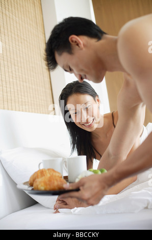 Woman in bed, man bringing breakfast tray Stock Photo