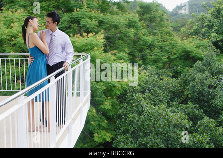 Couple standing on balcony, embracing Stock Photo