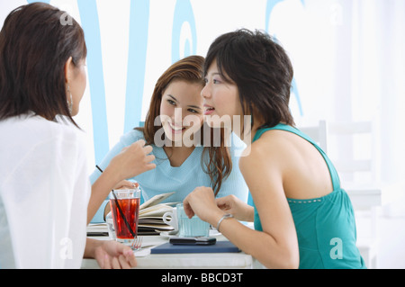 Three young women sitting in cafe, talking Stock Photo