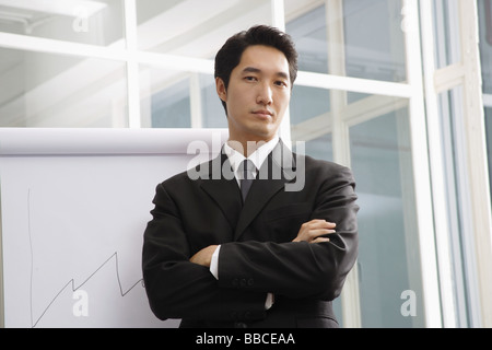 Businessman standing next to flipchart, looking at camera Stock Photo