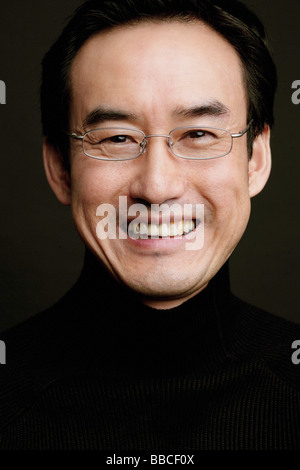 Man with glasses, smiling, head shot, black background Stock Photo
