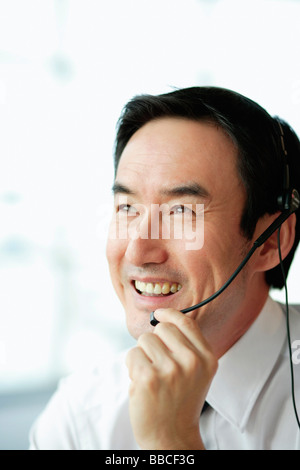 Businessman using headset, smiling, looking away Stock Photo