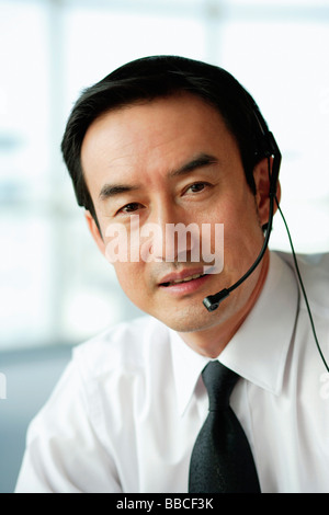 Businessman using headset, looking at camera Stock Photo