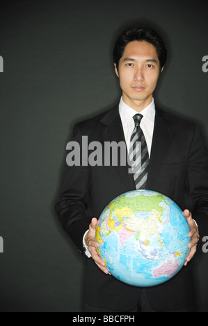 Businessman standing, holding globe in two hands Stock Photo
