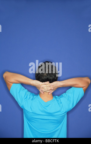 Man standing with hands behind head, rearview Stock Photo